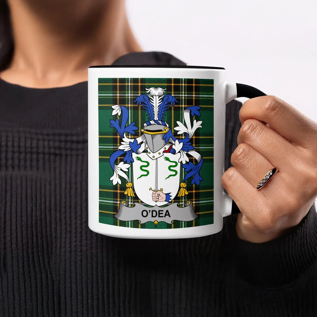 Mug with O'Dea family crest on plaid background held by a person.