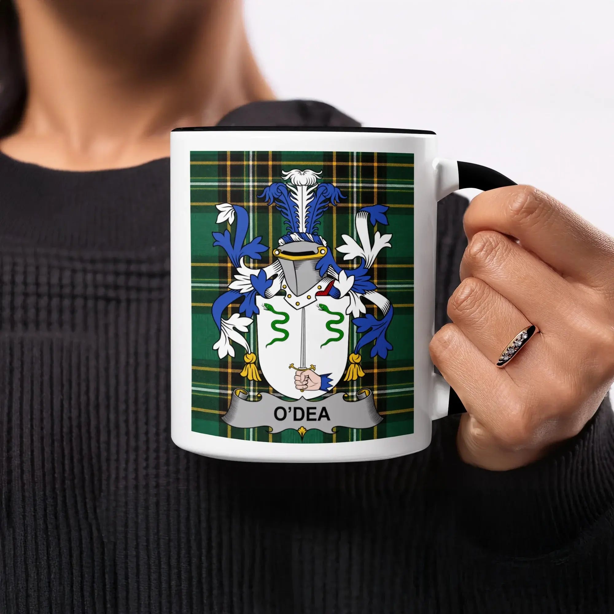 Mug with O'Dea family crest on plaid background held by a person.