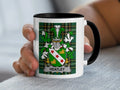 White mug with black rim featuring a green plaid background and a coat of arms.