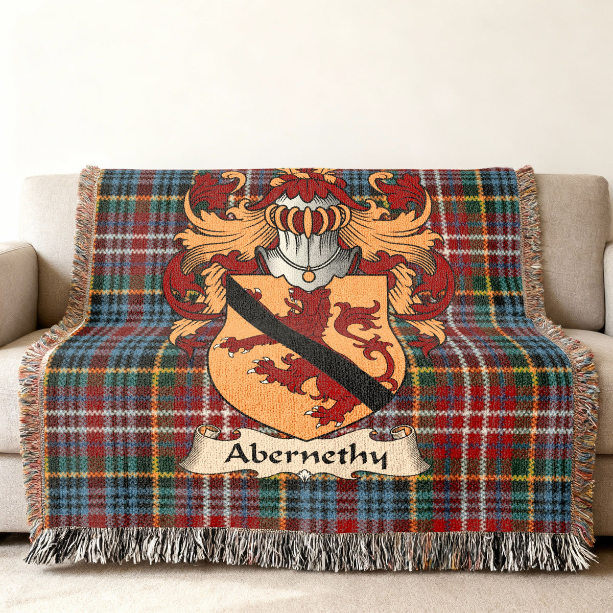 Abernethy Scottish family shield woven blanket with Caledonia tartan background on a sofa