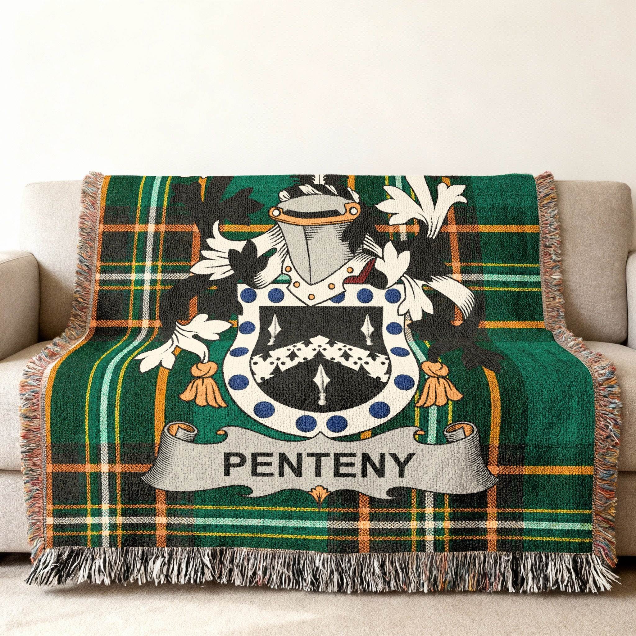Green plaid throw blanket with Penteny family crest on a couch.