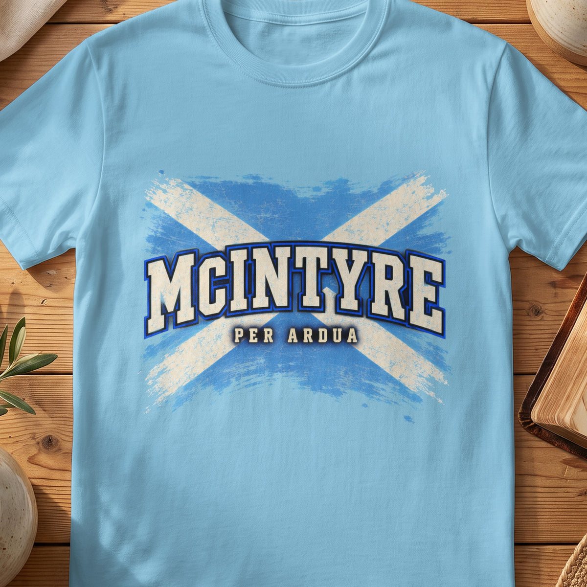 McIntyre Scottish Saltire T-shirt in Sky, with distressed blue and cream flag and “Per Ardua” lettering.