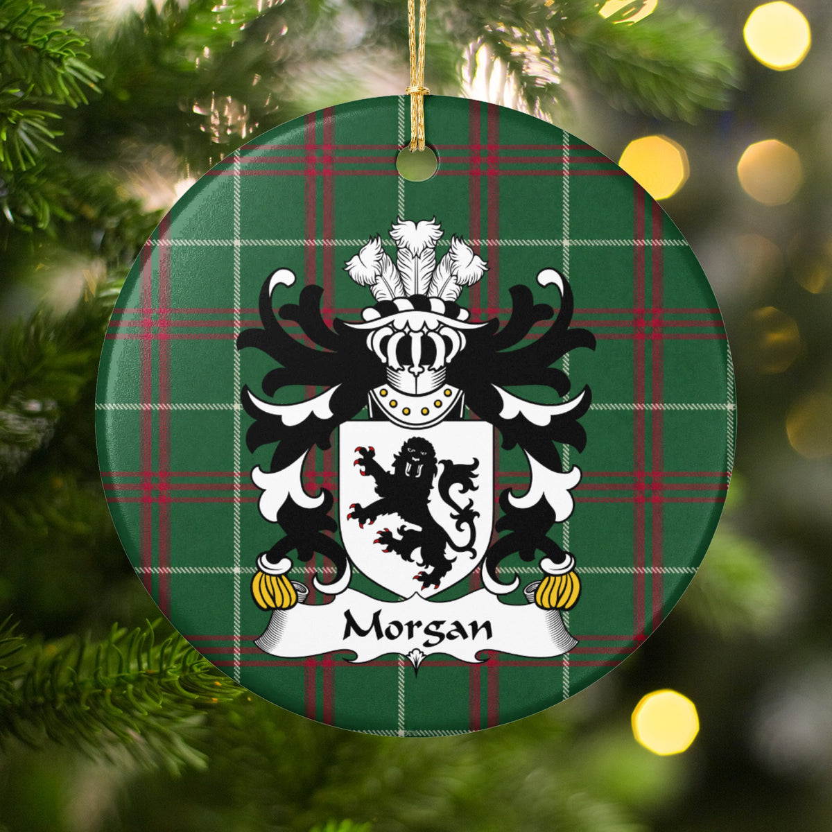 Morgan ornament, Style 2 hanging among Christmas tree branches and warm lights; a black lion on a white shield on Welsh national tartan.