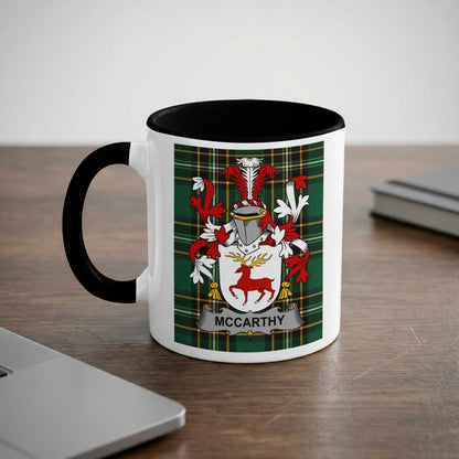 Mug with McCarthy family crest on a wooden desk next to a laptop.
