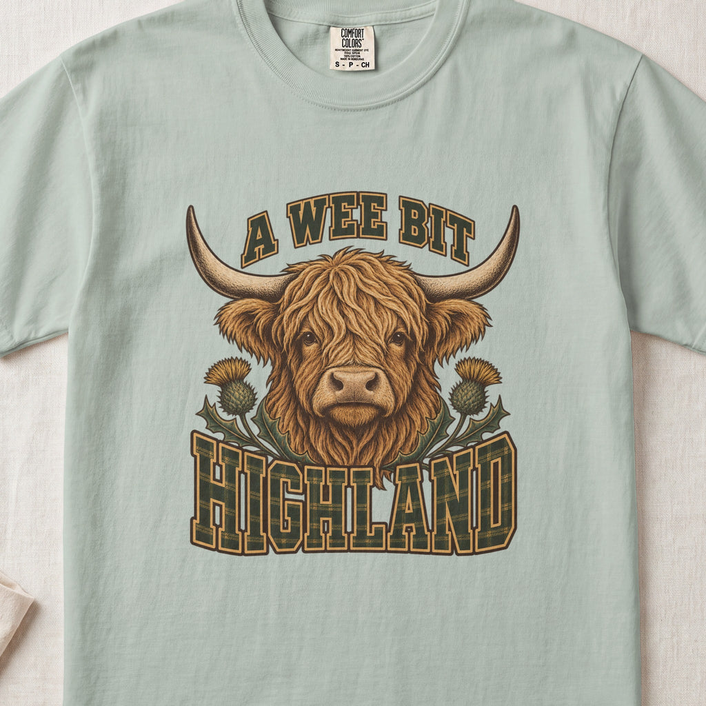 A Wee Bit Highland Highland cow design on a Bay Comfort Colors 1717 T-shirt, flat lay