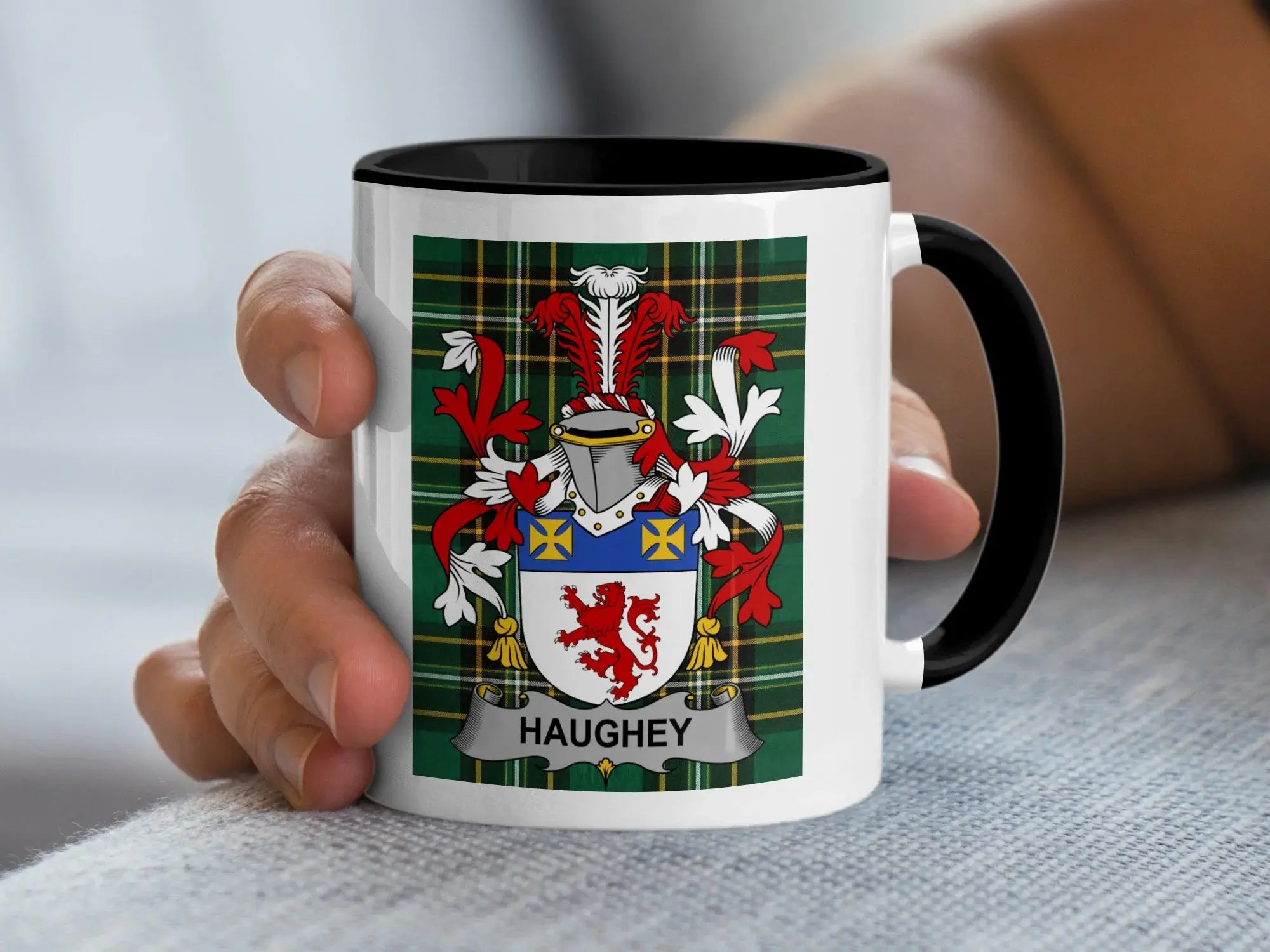 White mug with black rim featuring the Haughey family crest on a tartan background.