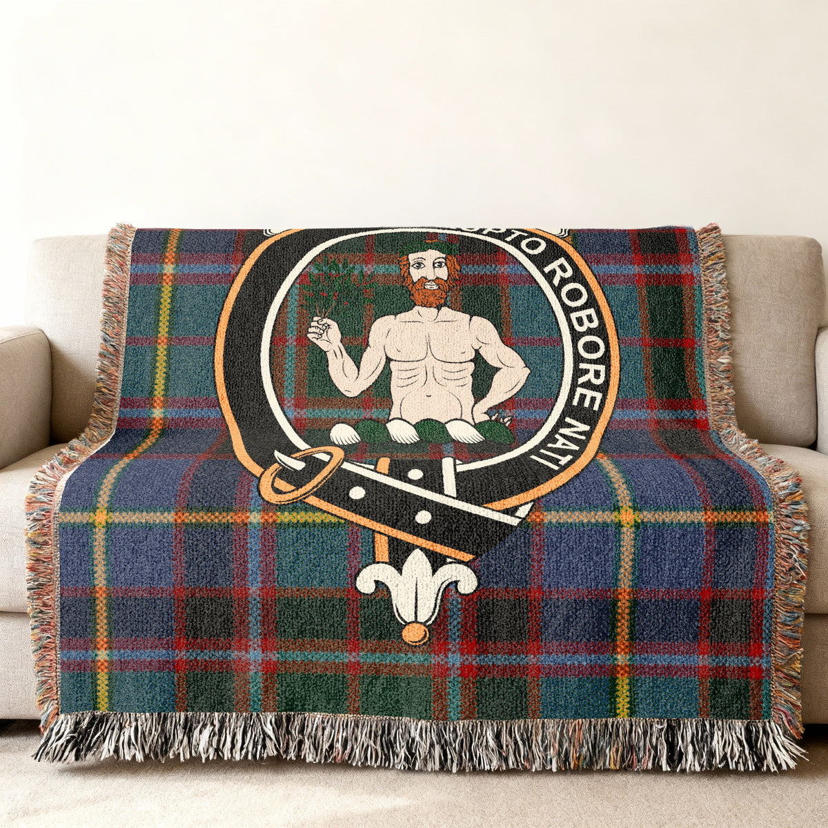 Close view of the Aikenhead woven blanket draped over a sofa, showing the crest and fringed edges