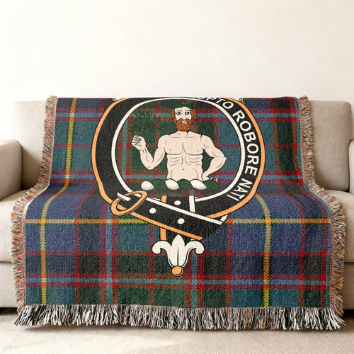 Close view of the Aikenhead woven blanket draped over a sofa, showing the crest and fringed edges