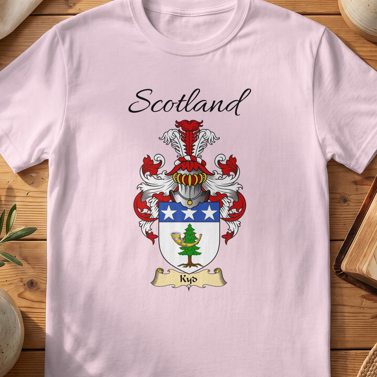 Light Pink Kyd Scottish family shield T-shirt featuring a blue top band with white stars above a green motif
