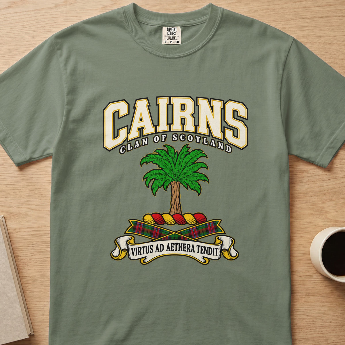 Cairns clan crest with green palm tree on a sage green Comfort Colors T-shirt, front view