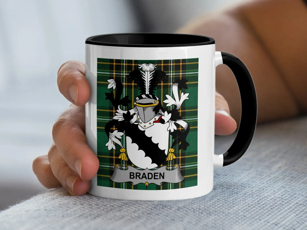Mug with Braden family crest and black handle held by a hand.