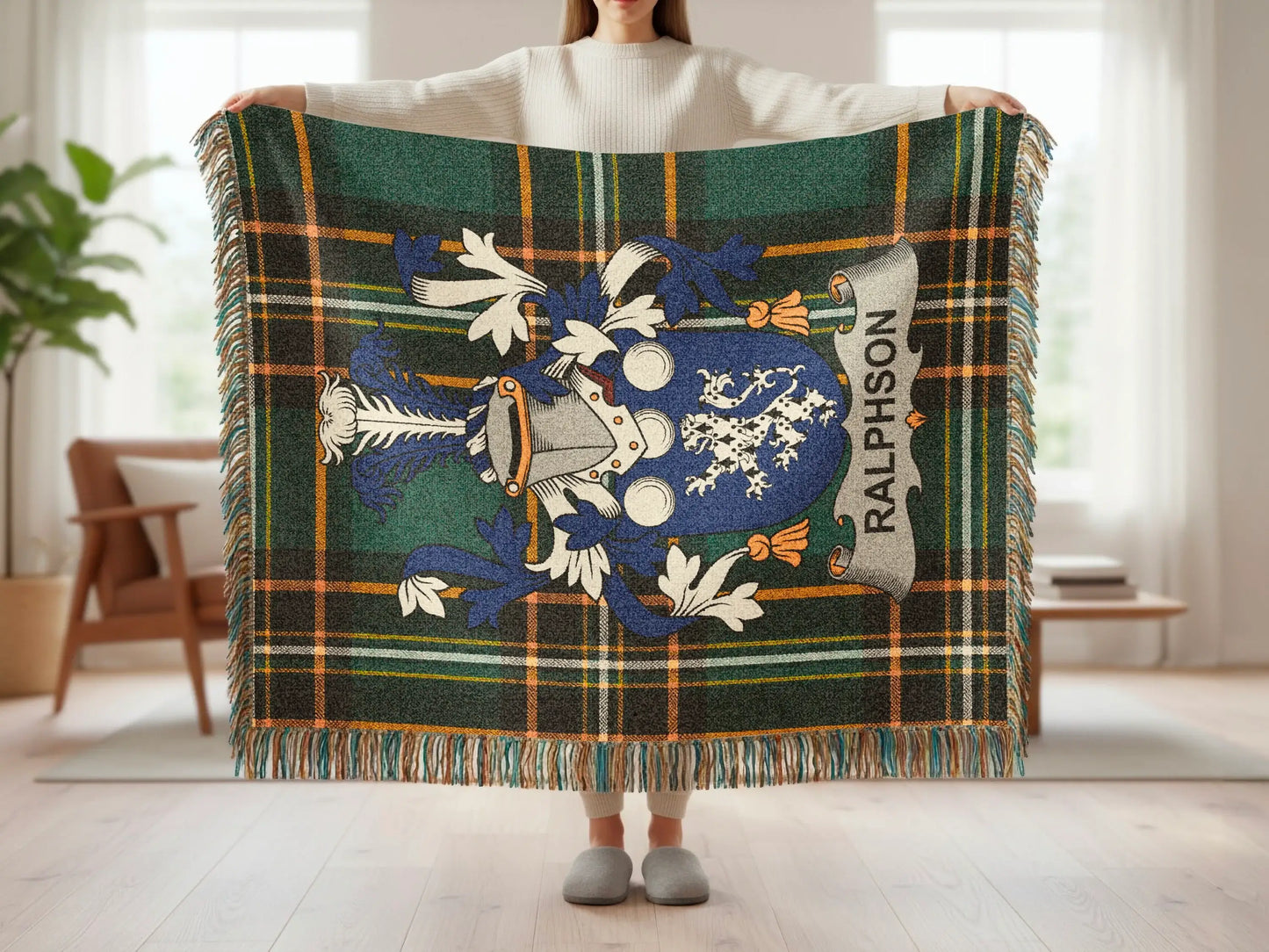 Tartan blanket with Ralposon crest and fringe held by person.