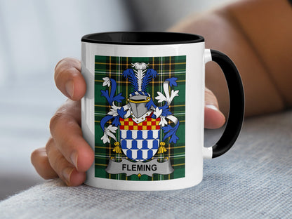 White mug with black rim displaying the Fleming family crest on a tartan background.