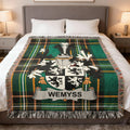 Wemyss family crest on a green plaid throw blanket on a bed.