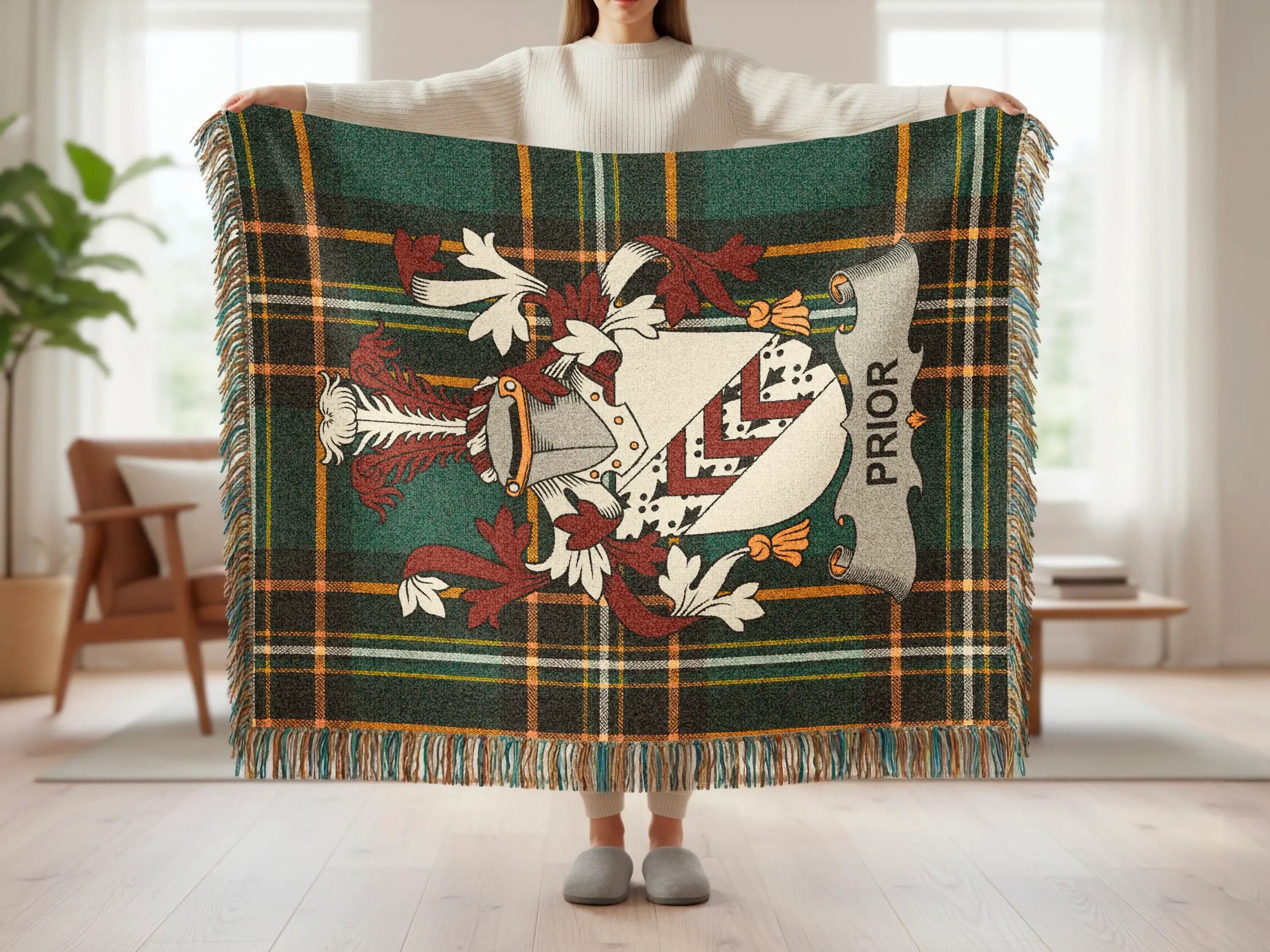 Green tartan blanket with crest and "PRIOR" text, held by person.