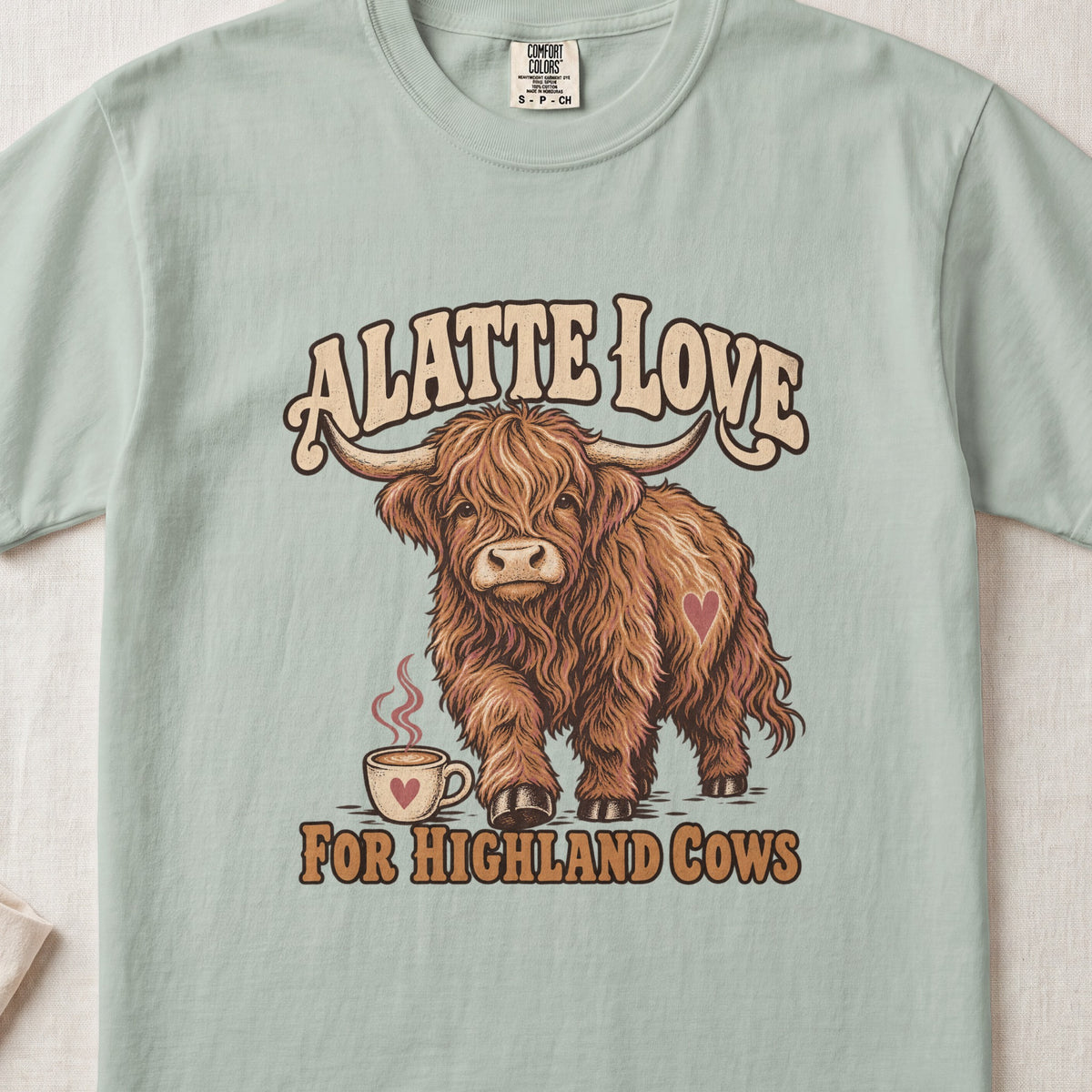 A Latte Love for Highland Cows Highland cow design on a Bay Comfort Colors 1717 T-shirt, flat lay