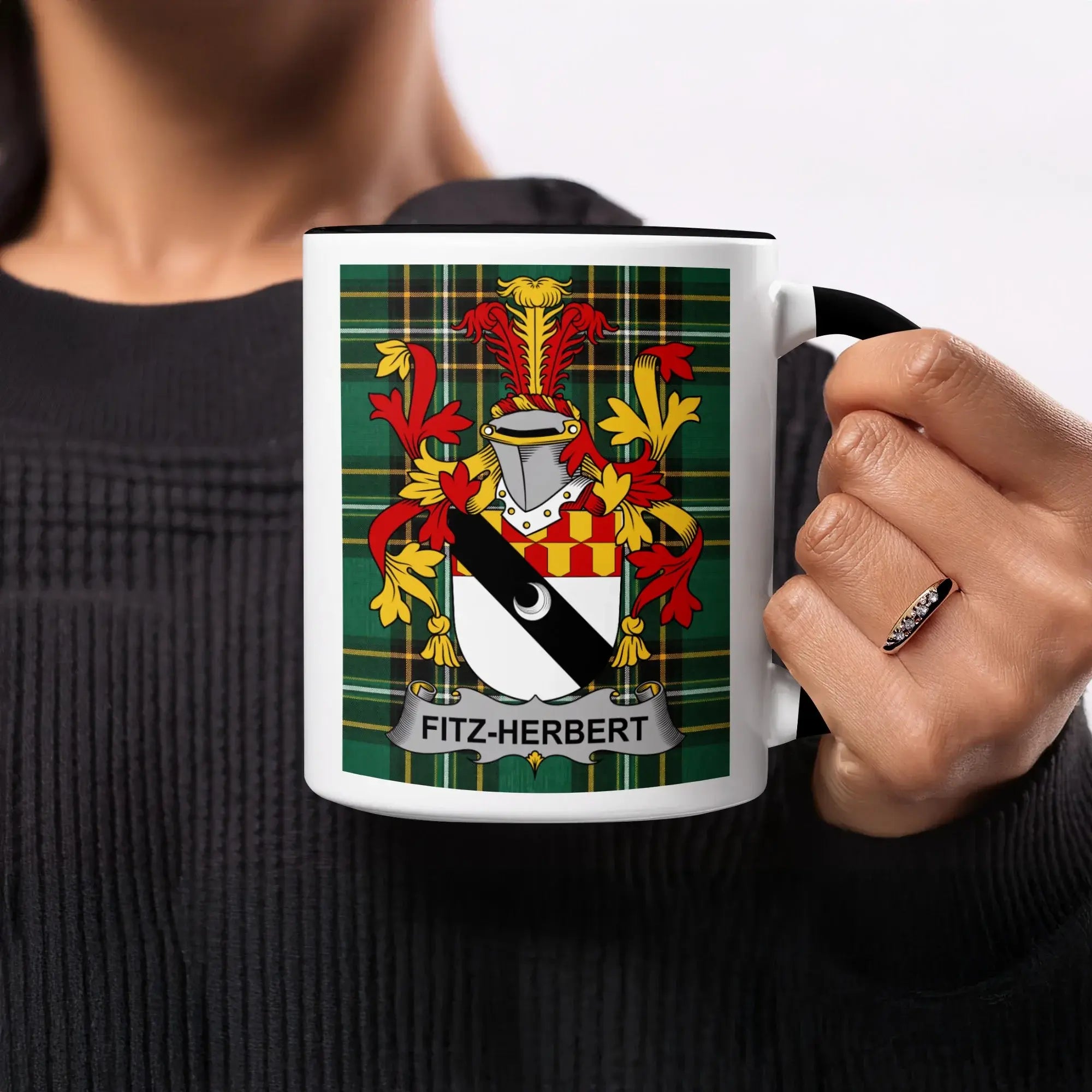 Fitz-Herbert crest on a black and white mug held by a person.