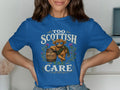 Blue t-shirt with Highland cow graphic, wearing sunglasses and scarf, holding whisky barrel.