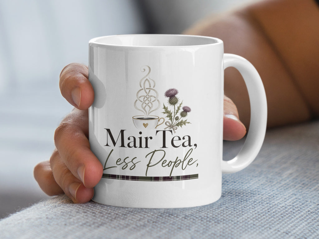 White mug with Mair Tea, Less People text and Scottish thistle design.