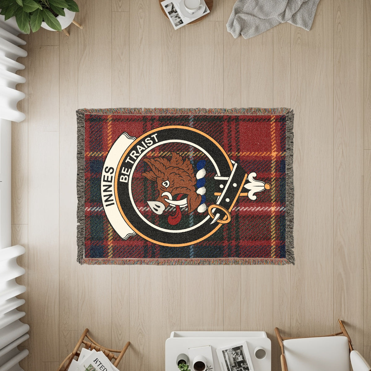 Innes woven blanket displayed on a wall, featuring the crest badge and tartan background