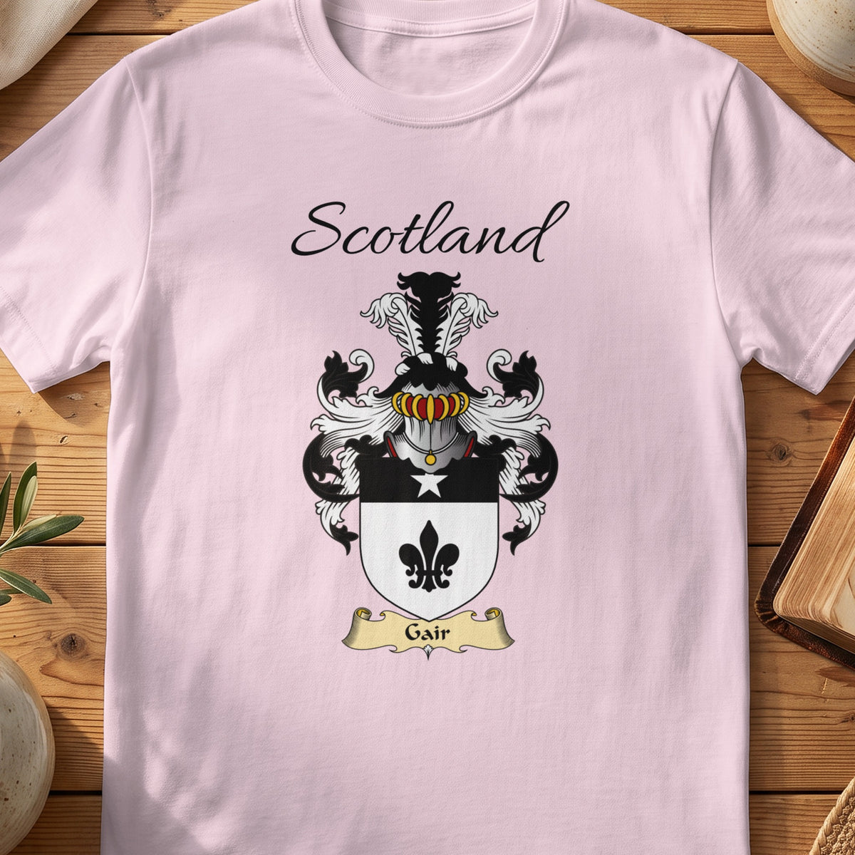 Light Pink Gair Scottish family shield T-shirt featuring a black fleur-de-lis on a pale shield