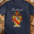 Navy Maxton family shield T-shirt featuring a red diagonal band and blue motifs on gold