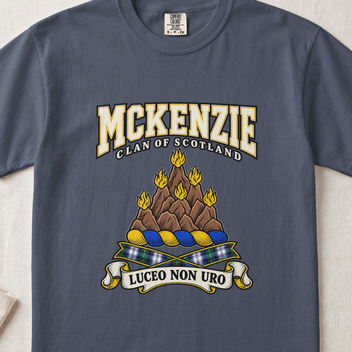 McKenzie graphic T-shirt in Midnight blue, front flat lay showing varsity lettering and brown rocky mountain-like mound with yellow flames.