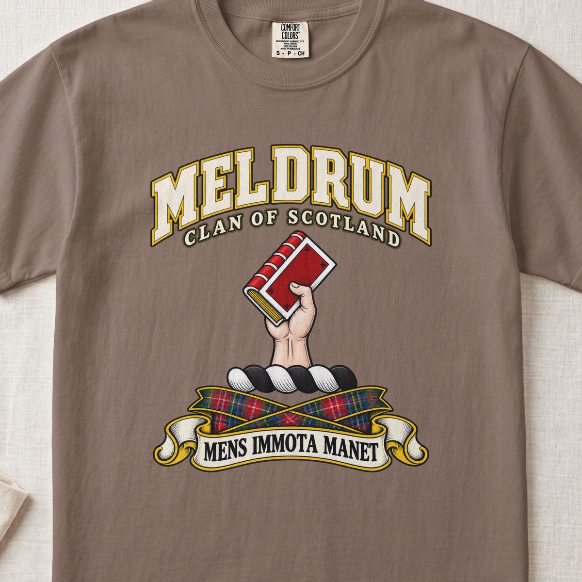 Meldrum Scottish clan T-shirt in Espresso, front view with a hand holding a red book and motto banner.