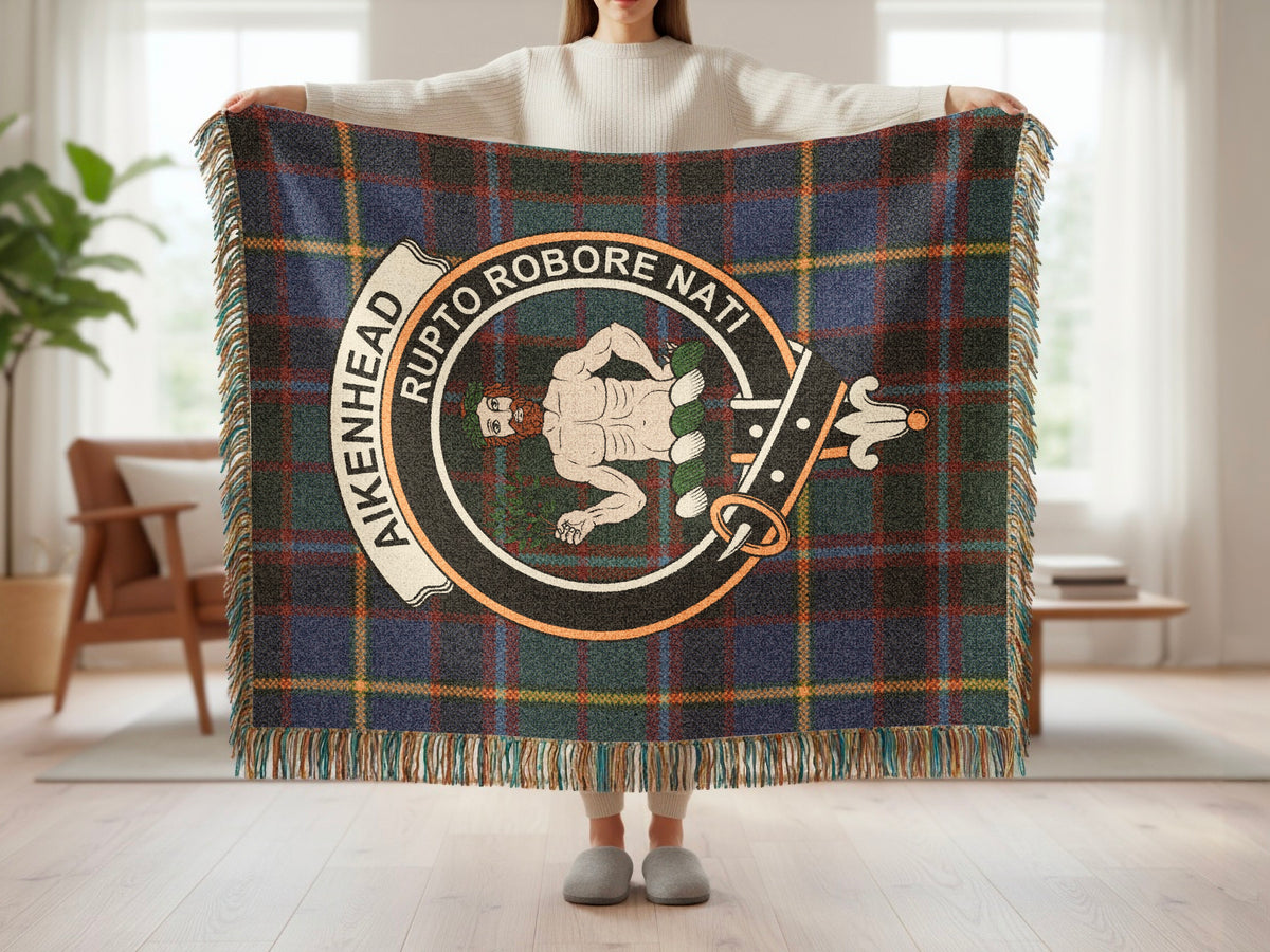 Person holding the Aikenhead woven blanket to show the full design, tartan background and fringe