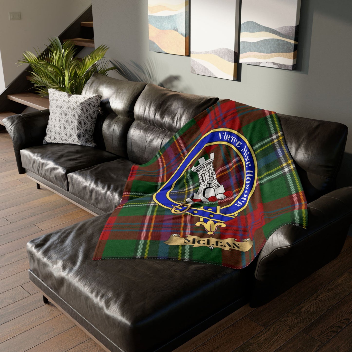 McLean tartan plaid blanket with clan crest draped on a leather sofa.