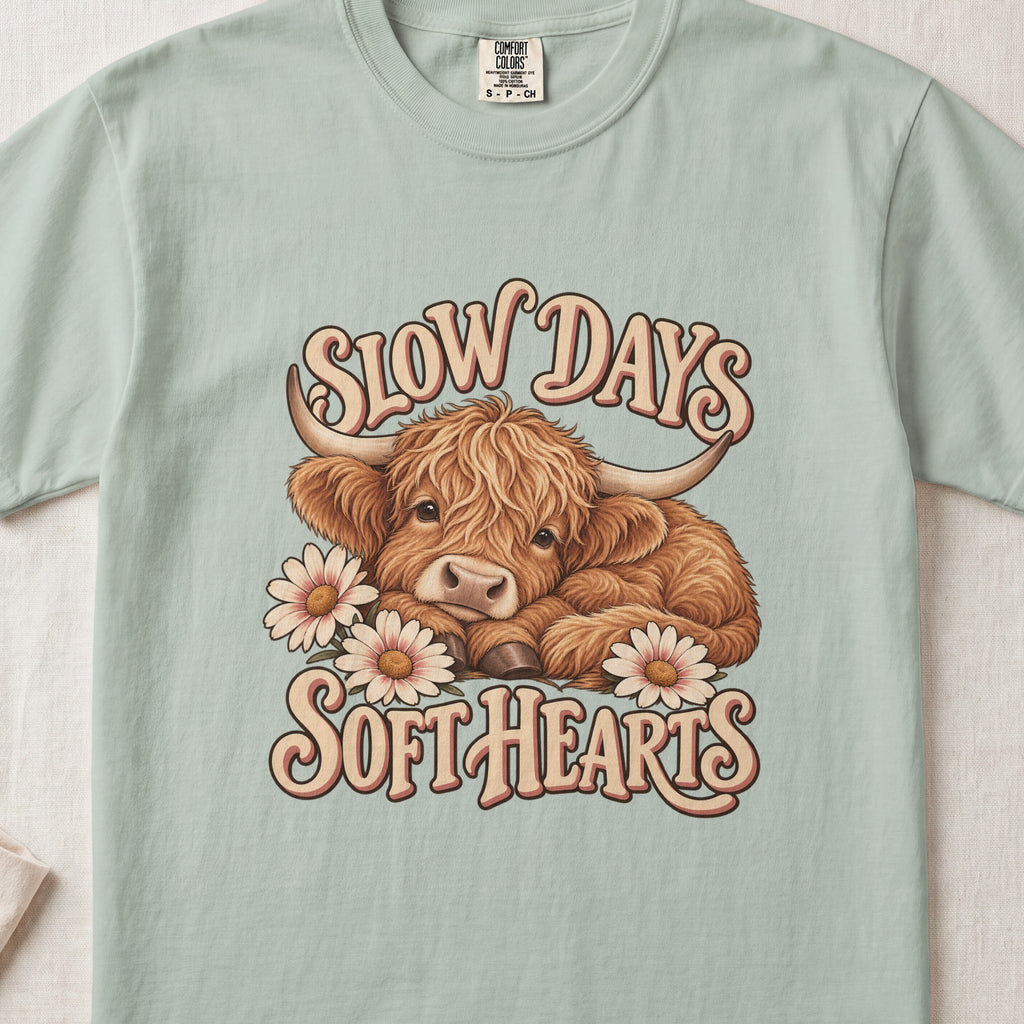 Slow Days, Soft Hearts Highland cow design on a Bay Comfort Colors 1717 T-shirt, flat lay