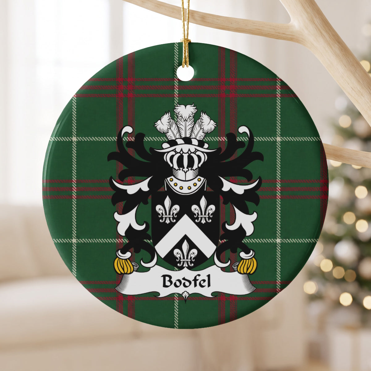 Bodfel ornament hanging from a pale wooden branch; a white chevron between three white fleurs-de-lis on black on Welsh national tartan.
