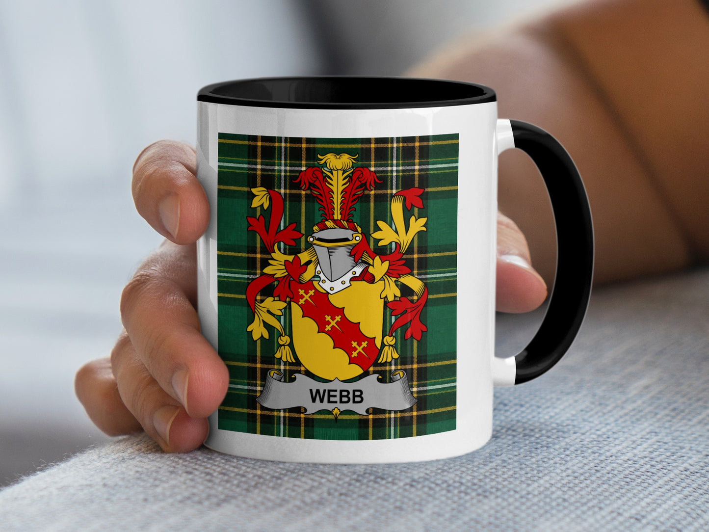 White mug with black rim displaying a red and yellow Webb family crest on a tartan background.