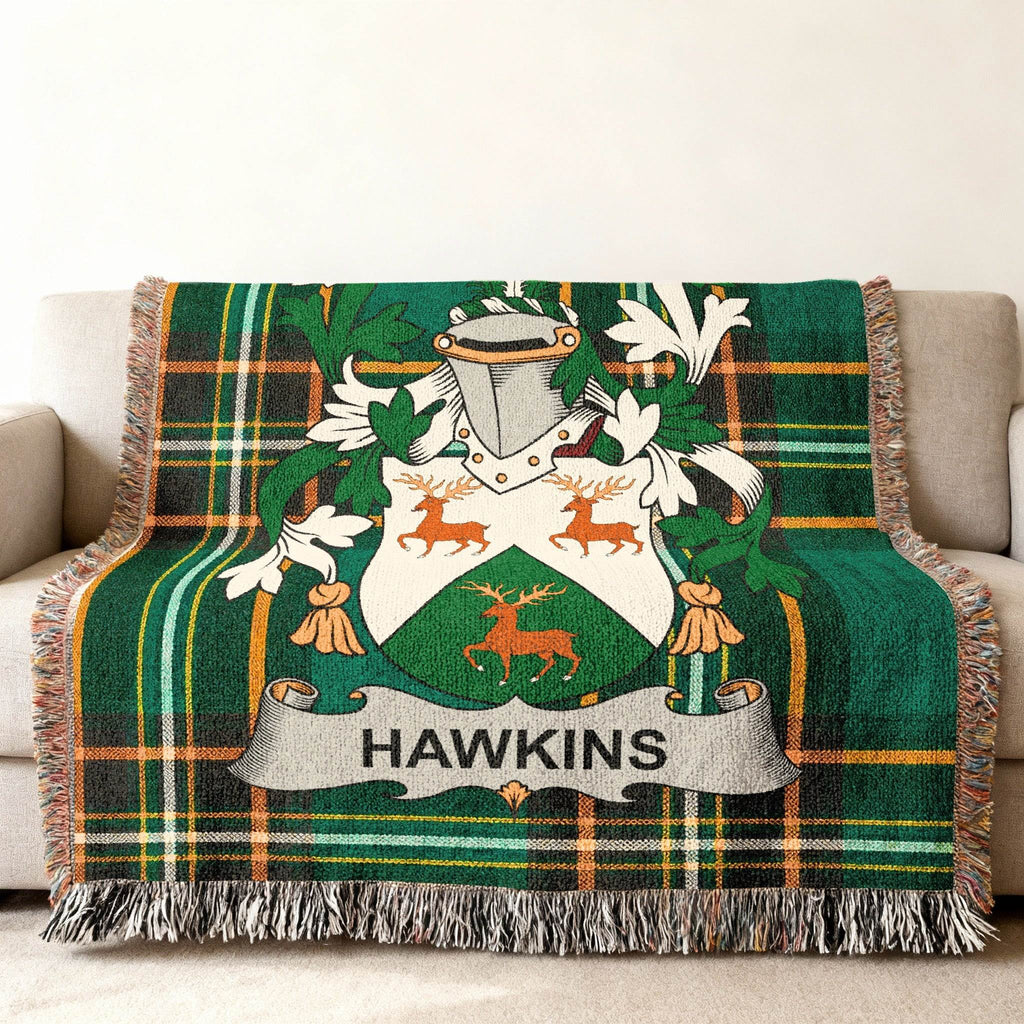 Hawkins family crest on a green tartan plaid blanket draped on a sofa.