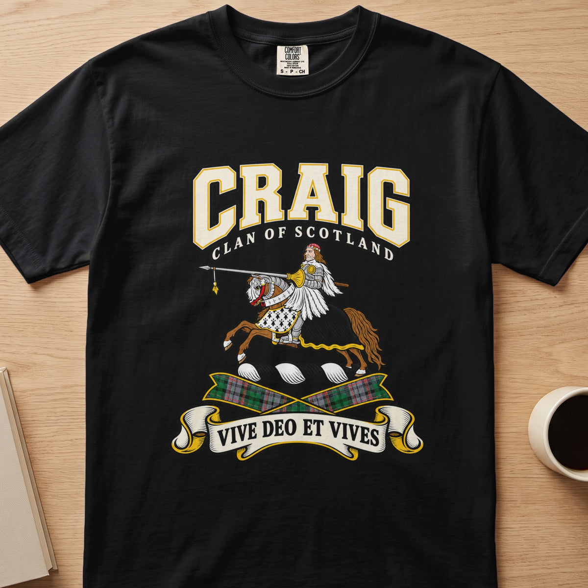 Craig winged creature crest and tartan ribbons graphic on a black Comfort Colors T-shirt, front view