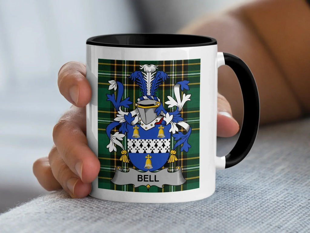 White mug with black rim displaying the Bell family crest on a plaid background.