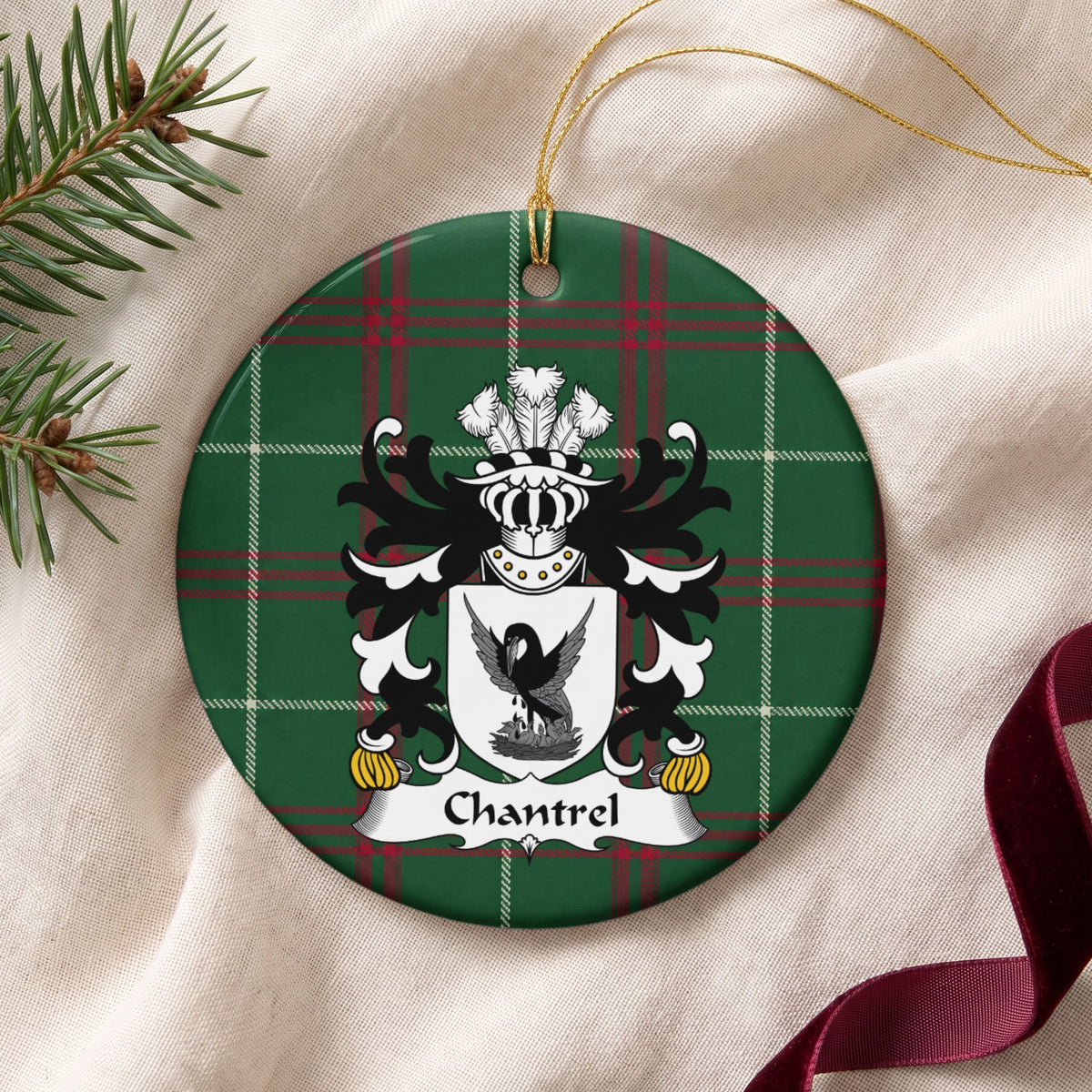 Chantrel ornament on cream fabric with gold string, evergreen and burgundy ribbon; a dark bird with raised wings above a nest on a white shield on Welsh national tartan.