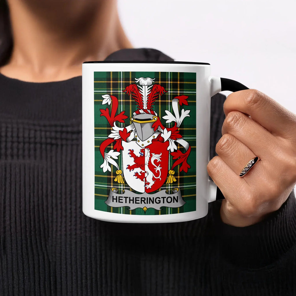 Hetherington tartan mug with a coat of arms and a person's hand holding it.