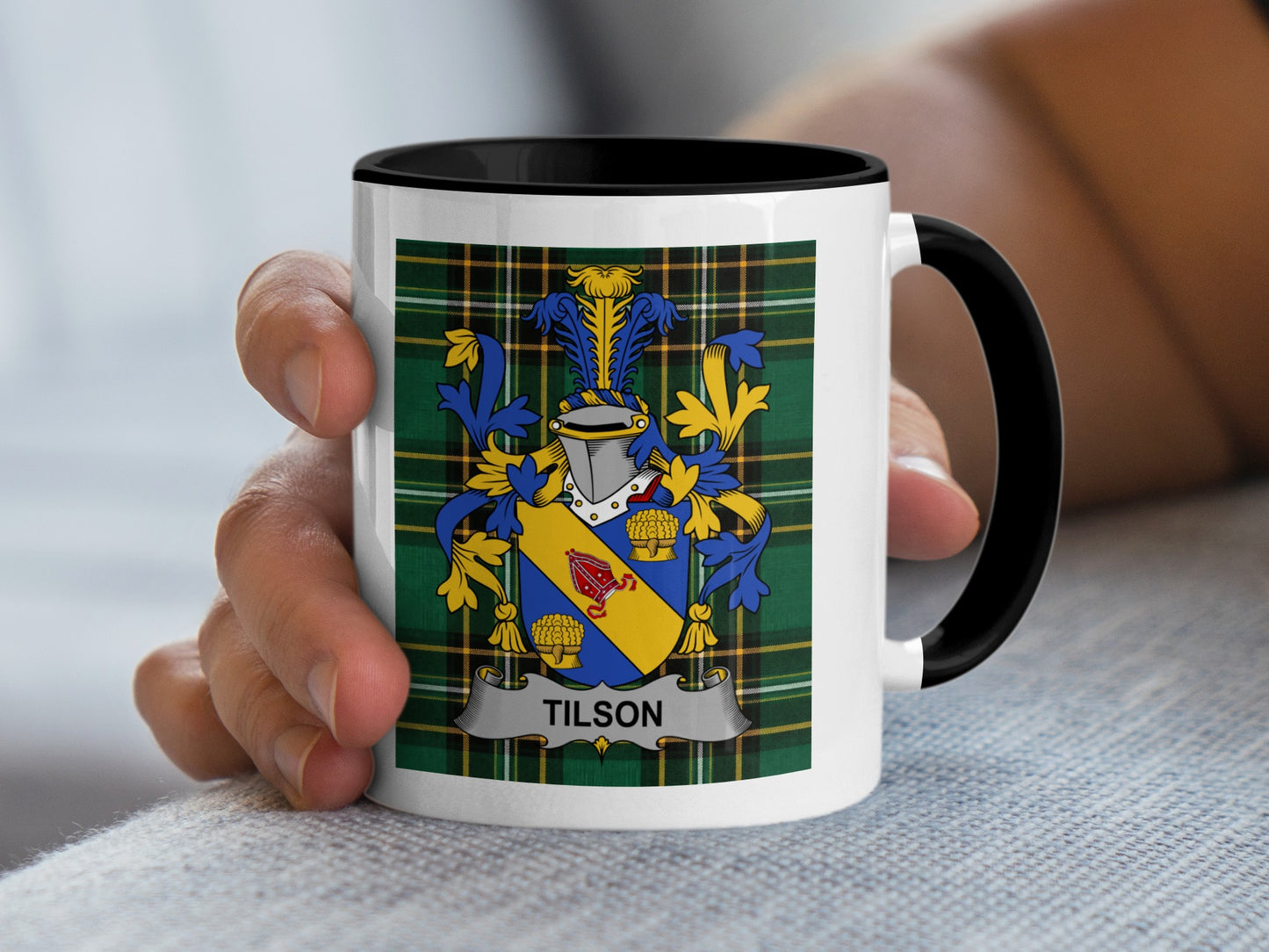 Mug with Tilson family crest in blue, yellow, and gold on plaid background.