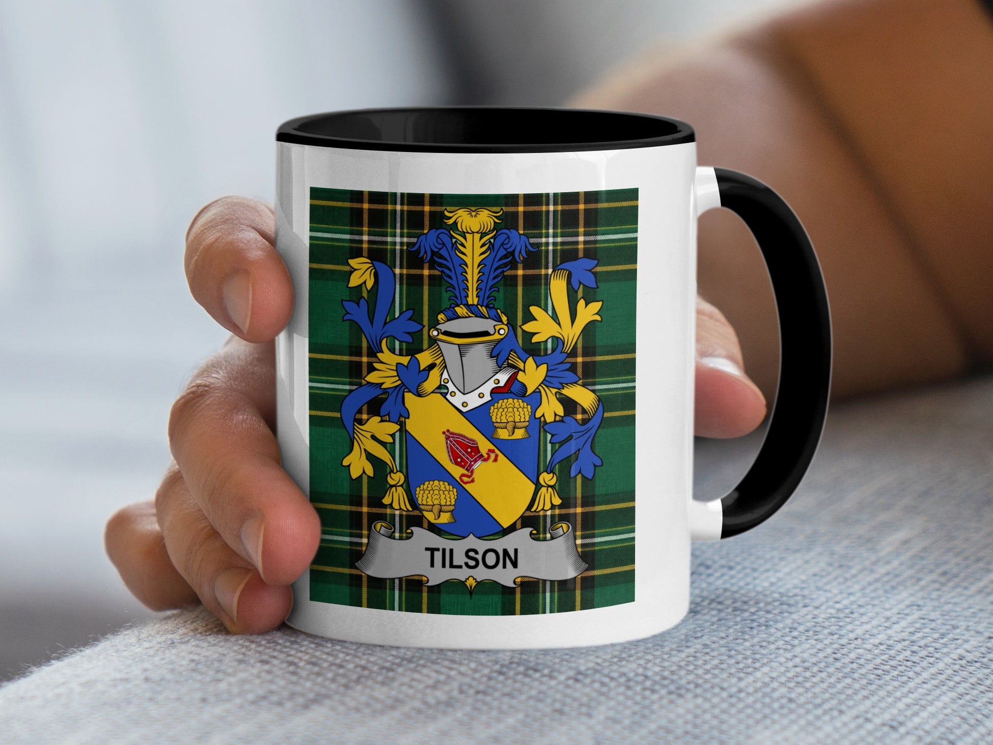 Mug with Tilson family crest in blue, yellow, and gold on plaid background.