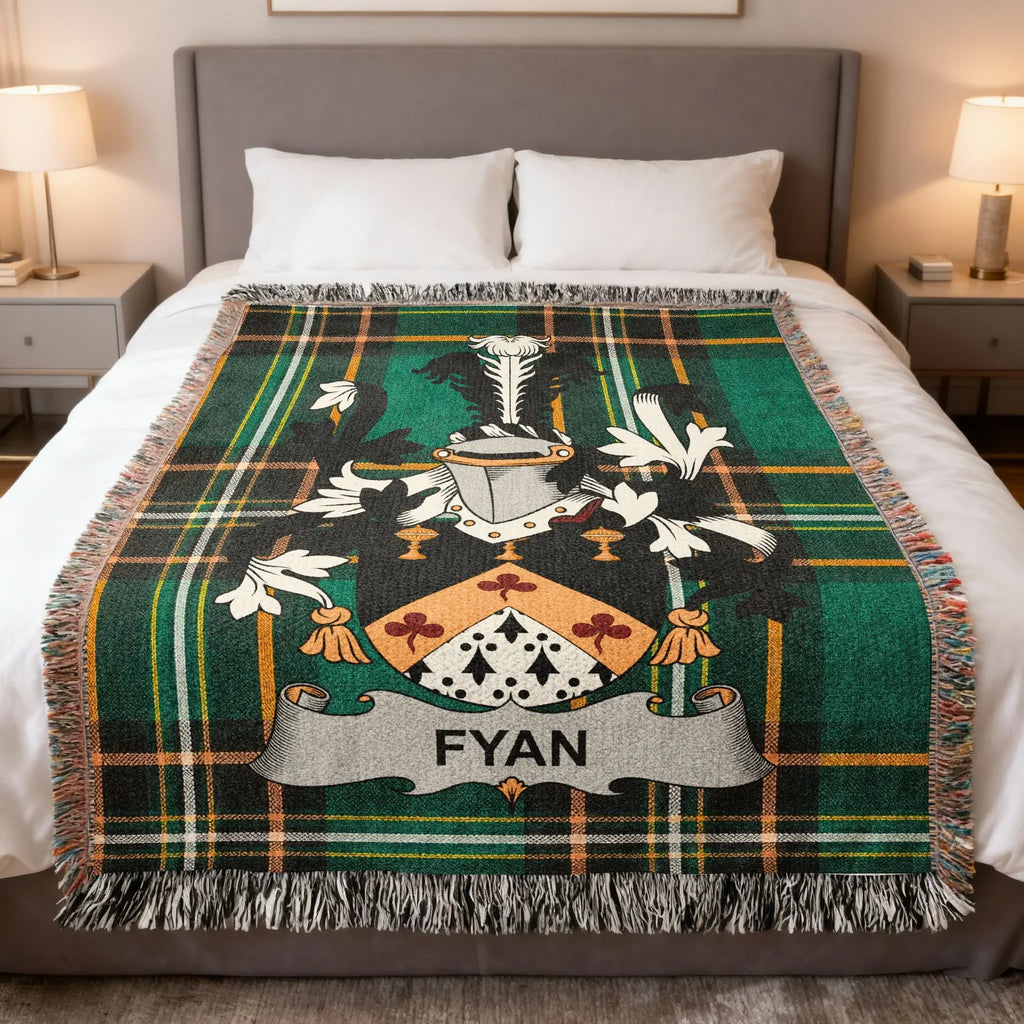 Green tartan blanket draped on a bed with a coat of arms featuring the name FYAN.