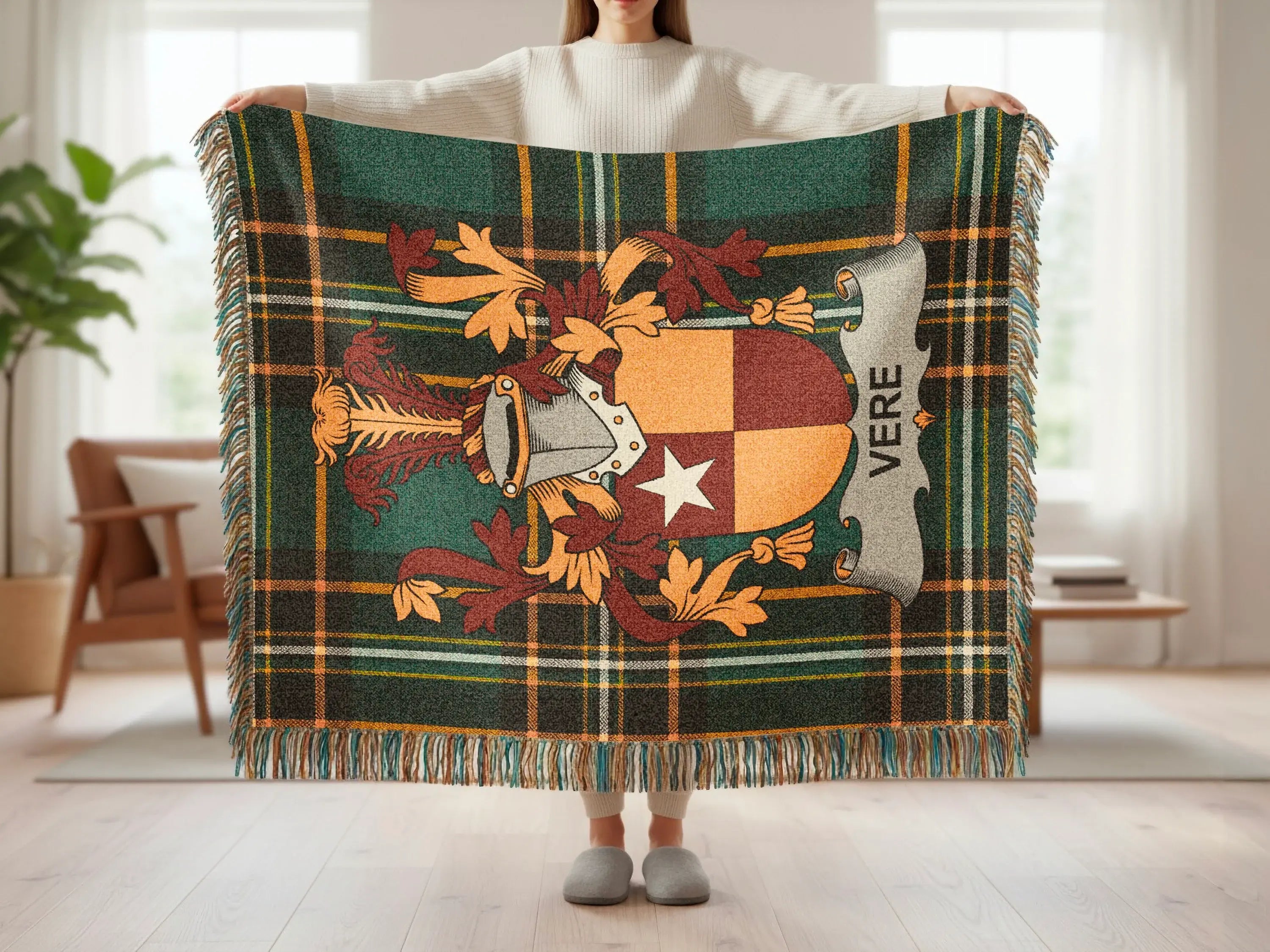 Tartan blanket with crest and "VERE" text held by a person.