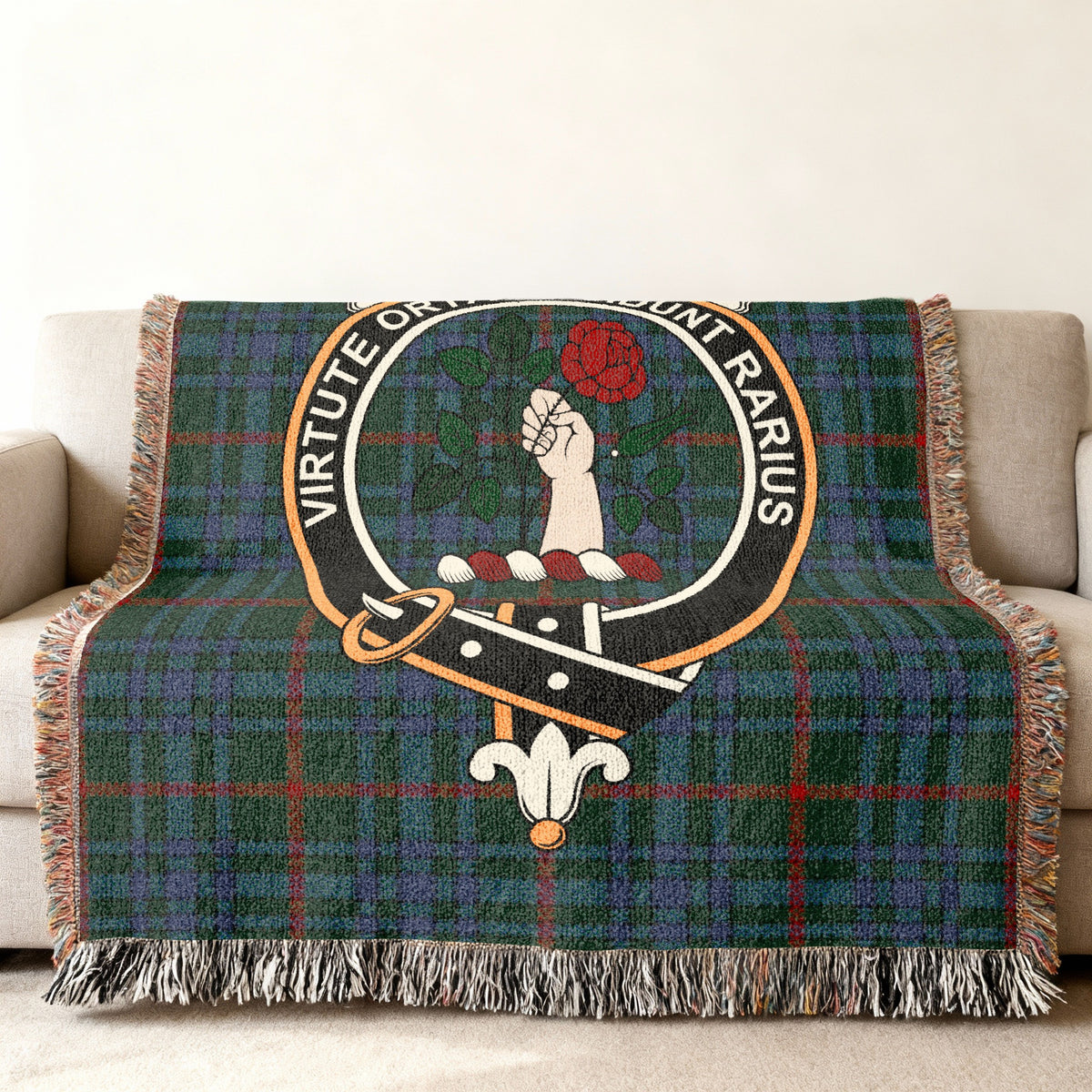 Close view of the Aiton woven blanket draped over a sofa, showing the crest and fringed edges