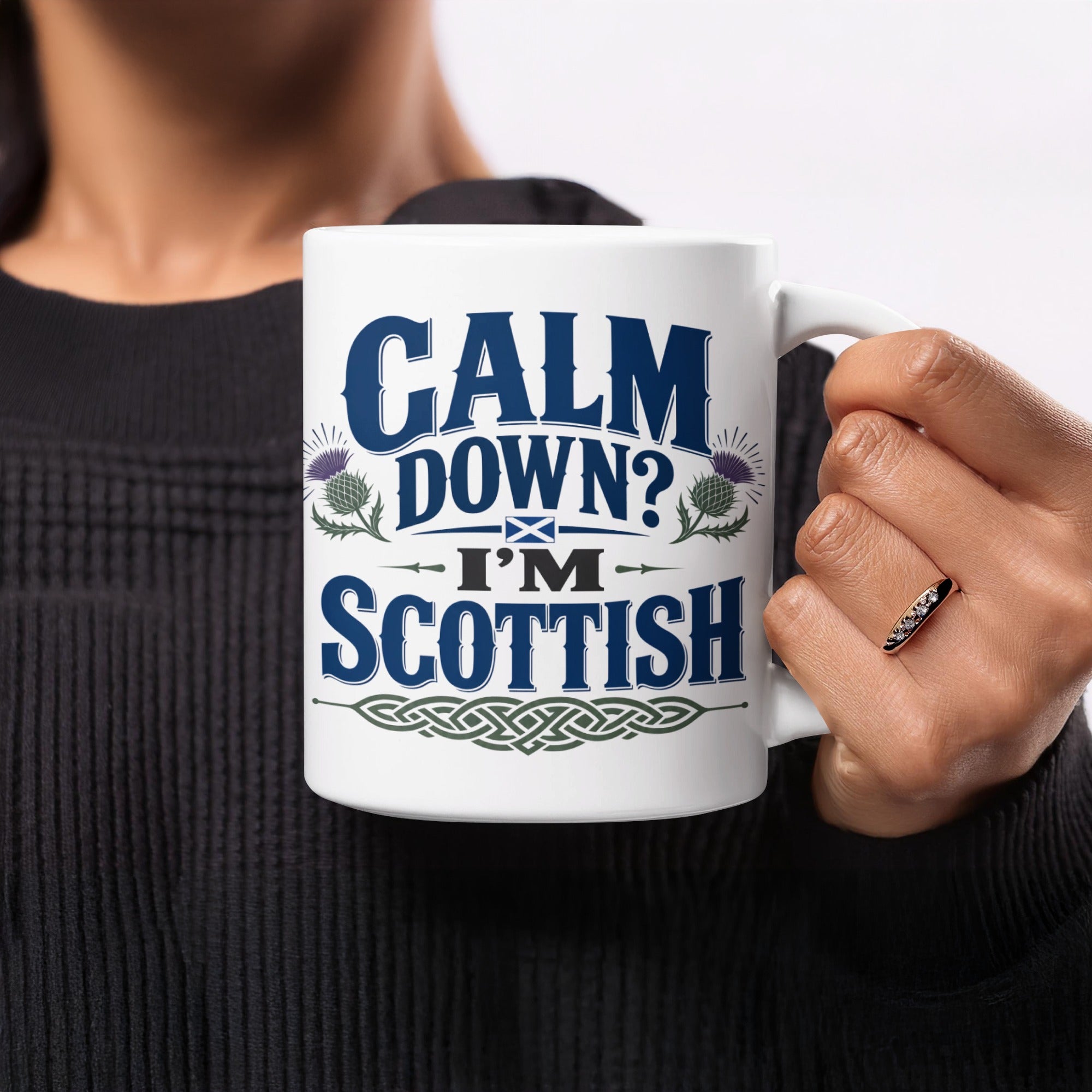 White mug with "Calm Down? I'm Scottish" in blue text and thistle designs.
