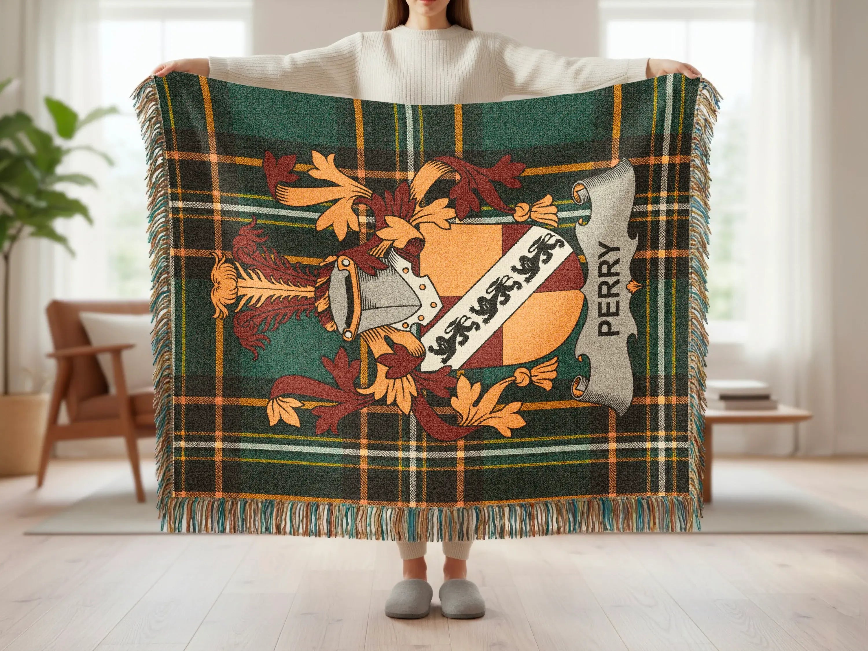 Tartan throw blanket with Perry family crest, held up by a person.