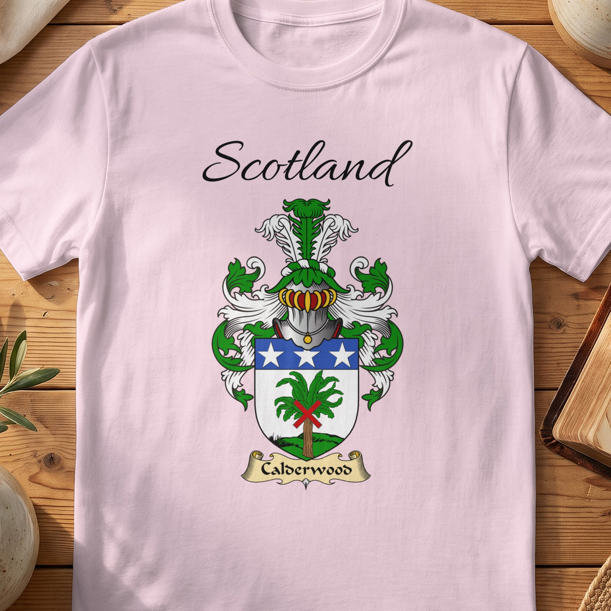 Light Pink Calderwood Scottish family shield T-shirt featuring a green tree beneath a blue band with white stars