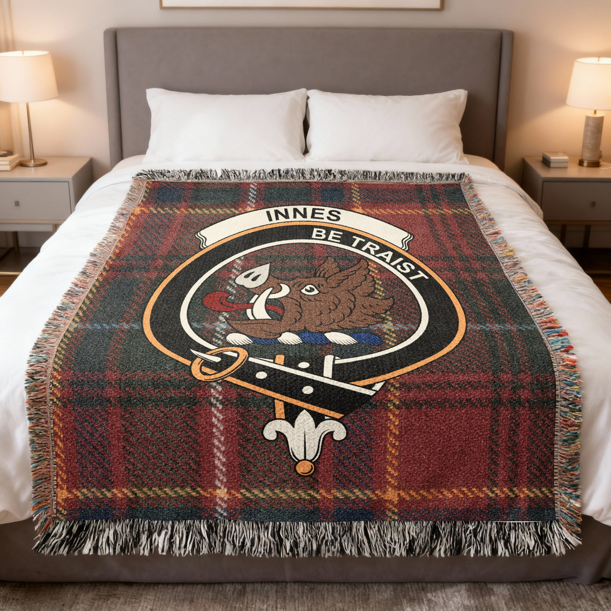 Innes woven blanket displayed on a bed, with a boar's head on a red, green and gold tartan background