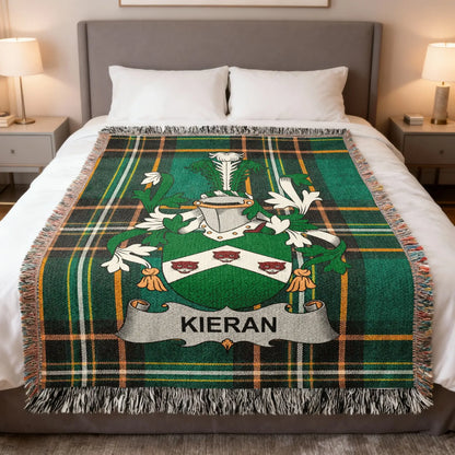 Tartan blanket with Kieran family crest and fringed edges on a bed.