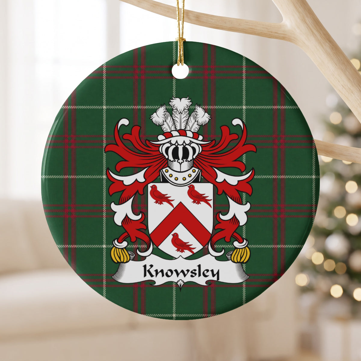 Knowsley ceramic ornament hanging from a pale wooden branch, showing a white shield with a red chevron and three red birds on Welsh national tartan.