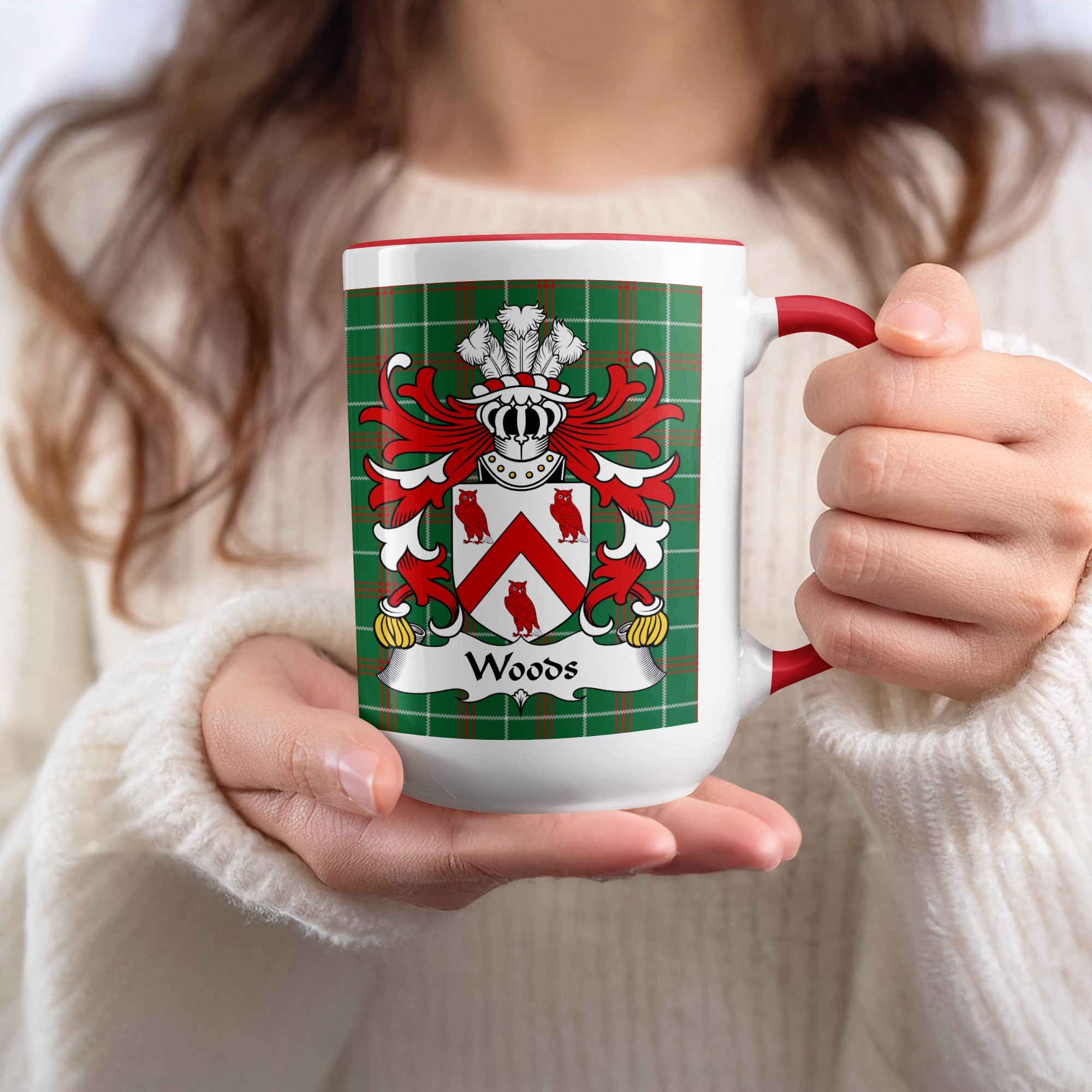 Mug with Woods family crest on green tartan pattern, held by person in sweater.